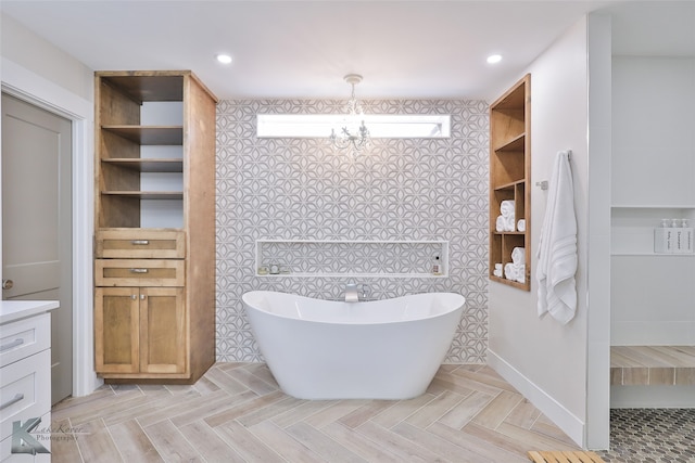 bathroom with a chandelier, a tub, and vanity