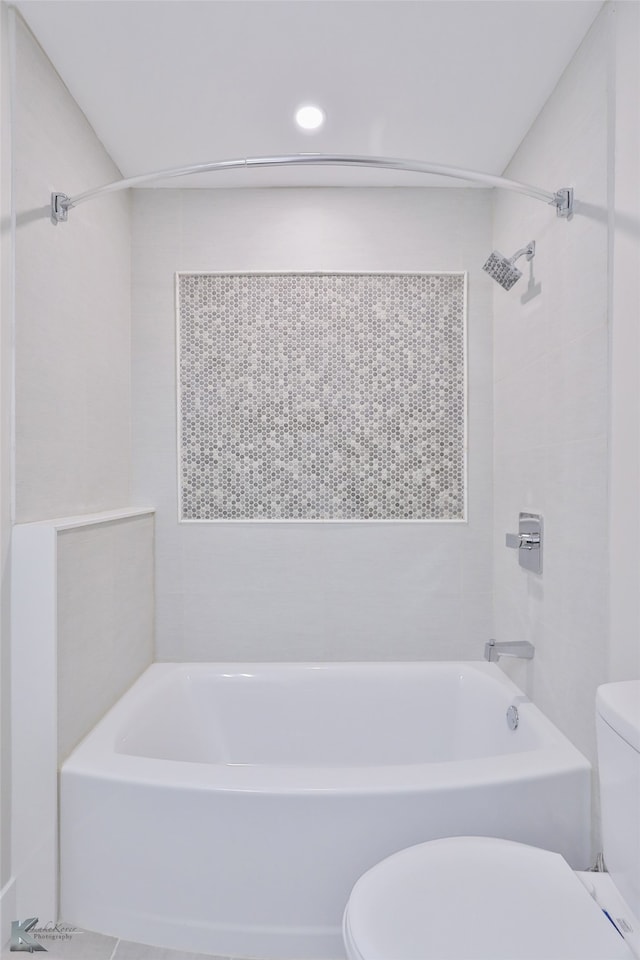 bathroom with tiled shower / bath combo and toilet