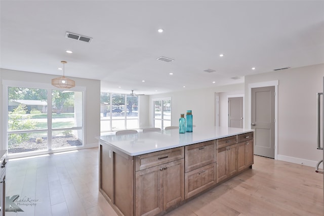 kitchen with a kitchen island, light hardwood / wood-style flooring, and decorative light fixtures