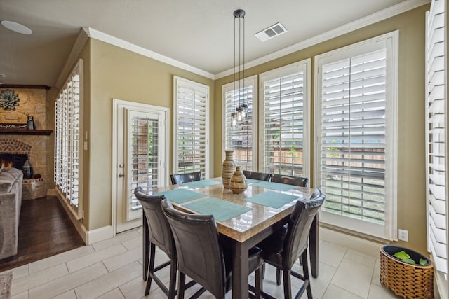 dining space with crown molding, light tile patterned floors, and a fireplace