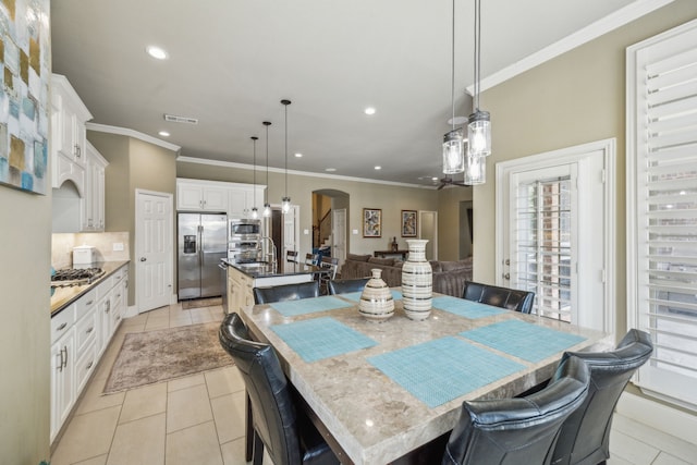 dining area with light tile patterned floors and ornamental molding