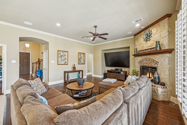 living room with a fireplace, dark hardwood / wood-style floors, ceiling fan, and ornamental molding