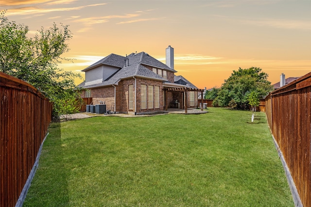 back house at dusk featuring a yard, central AC, and a patio area