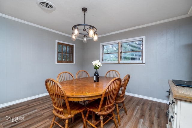 dining space featuring dark hardwood / wood-style flooring, ornamental molding, and a notable chandelier