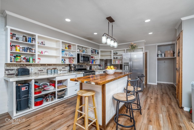 kitchen featuring wood counters, light hardwood / wood-style flooring, decorative light fixtures, white cabinetry, and stainless steel appliances