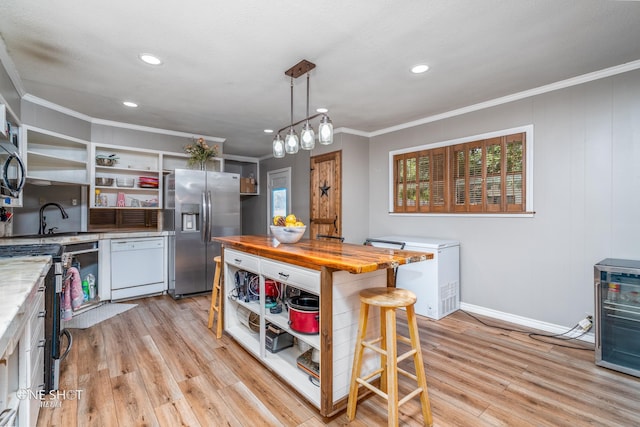 kitchen with pendant lighting, white cabinets, stainless steel appliances, and light hardwood / wood-style flooring