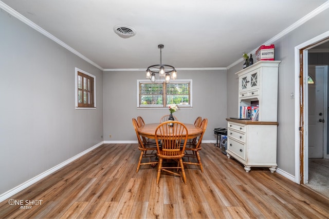 dining room with light hardwood / wood-style flooring, a notable chandelier, and crown molding