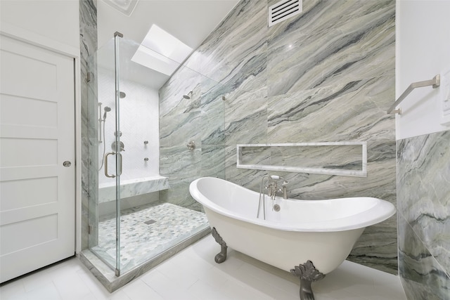 bathroom with tile patterned floors, a skylight, separate shower and tub, and tile walls