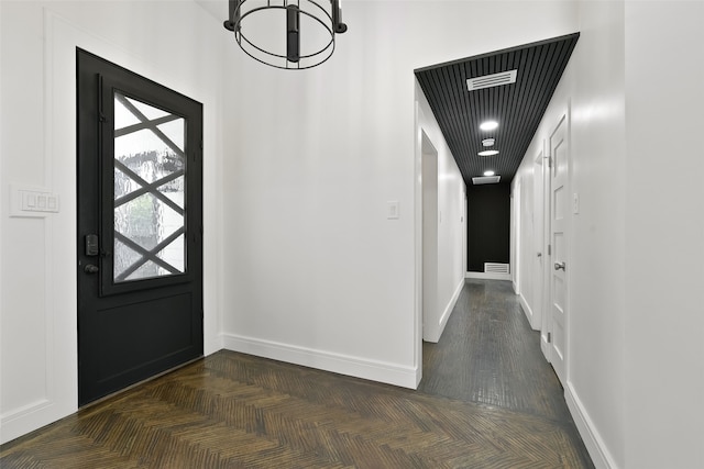 foyer with dark parquet floors and a chandelier