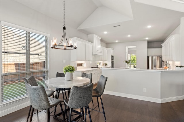 dining space with vaulted ceiling, dark hardwood / wood-style floors, sink, and a chandelier