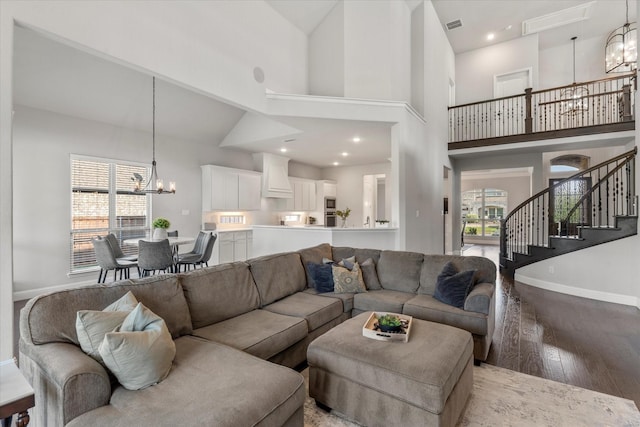 living room featuring a high ceiling, plenty of natural light, light wood-type flooring, and an inviting chandelier