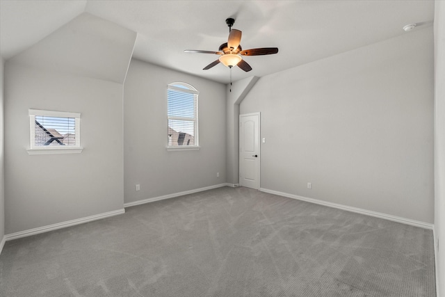 carpeted spare room featuring ceiling fan, lofted ceiling, and a wealth of natural light