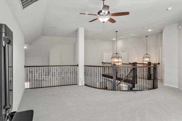 corridor with lofted ceiling, a notable chandelier, and light colored carpet