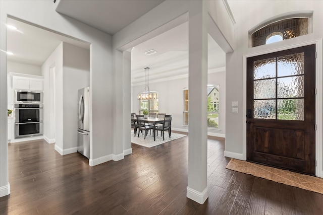 foyer with dark wood-type flooring and an inviting chandelier