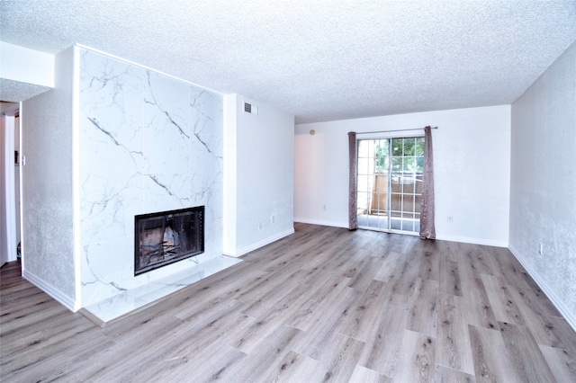 unfurnished living room featuring a fireplace, a textured ceiling, and light hardwood / wood-style floors