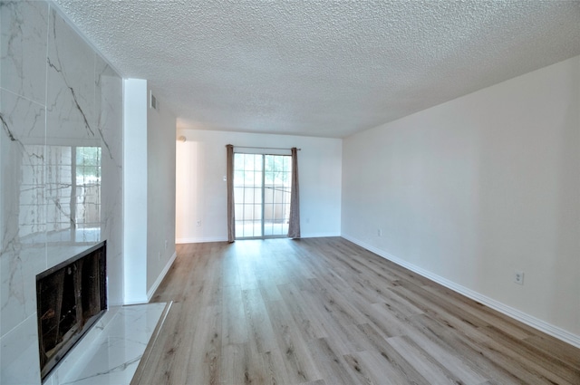 unfurnished living room featuring a fireplace, hardwood / wood-style floors, tile walls, and a textured ceiling