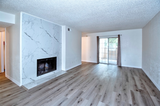 unfurnished living room featuring hardwood / wood-style flooring, a premium fireplace, and a textured ceiling