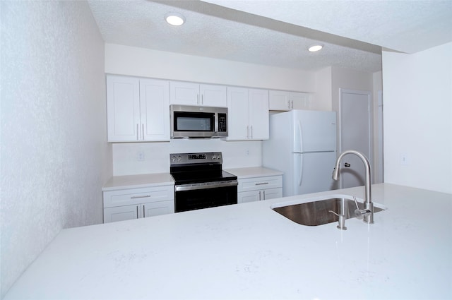 kitchen with appliances with stainless steel finishes, white cabinetry, a textured ceiling, and sink