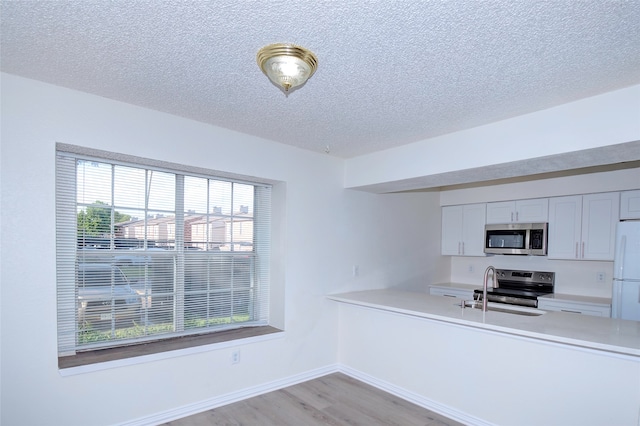 kitchen featuring white cabinets, stainless steel appliances, light hardwood / wood-style flooring, and plenty of natural light