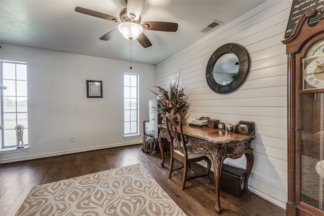 interior space with wood walls, ceiling fan, and dark hardwood / wood-style flooring