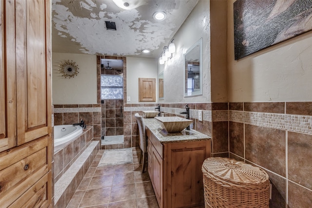 bathroom with tile walls, vanity, a textured ceiling, tile patterned flooring, and separate shower and tub