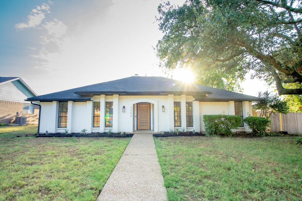 view of front of house with central AC and a front yard