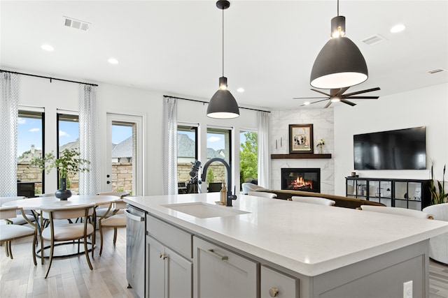 kitchen featuring a fireplace, light wood-type flooring, and an island with sink