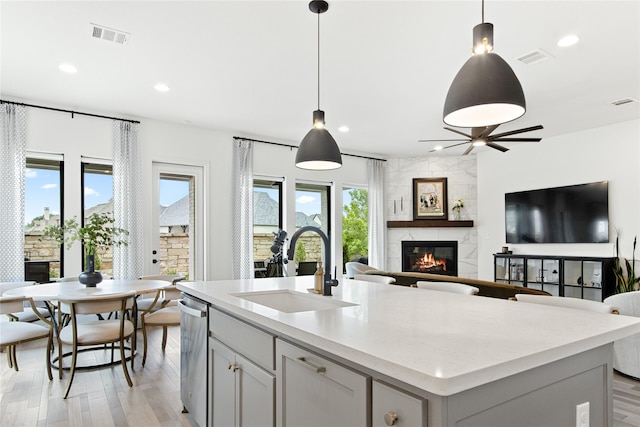 kitchen featuring visible vents, recessed lighting, a sink, a tiled fireplace, and open floor plan