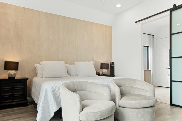 bedroom with a barn door and light wood-type flooring