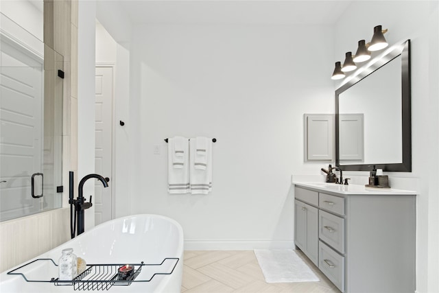 full bath with a stall shower, vanity, baseboards, and a freestanding tub