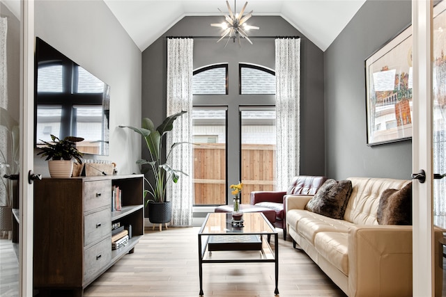 living area with vaulted ceiling, a notable chandelier, and light hardwood / wood-style floors