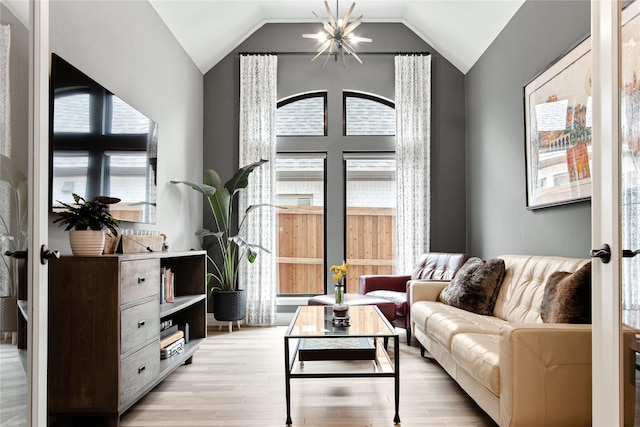 living area with lofted ceiling, light wood-style flooring, and a notable chandelier