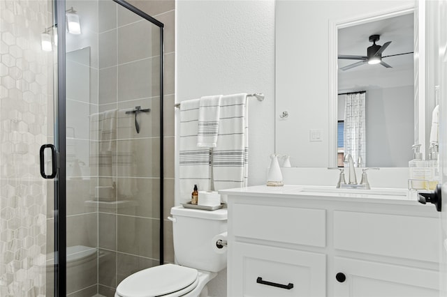 bathroom with a shower with shower door, toilet, vanity, and ceiling fan