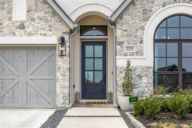 view of exterior entry with a garage and stone siding