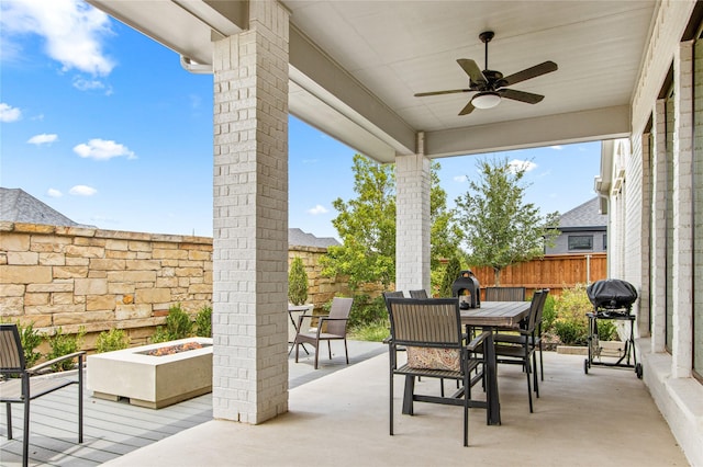 view of patio featuring outdoor dining space, fence, ceiling fan, a fire pit, and a grill