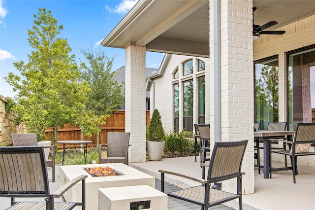 view of patio with a ceiling fan, outdoor dining area, fence, and an outdoor fire pit