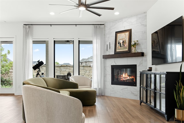 living room with plenty of natural light, a tiled fireplace, ceiling fan, and hardwood / wood-style floors