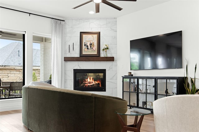 living area featuring a ceiling fan, wood finished floors, and a tile fireplace