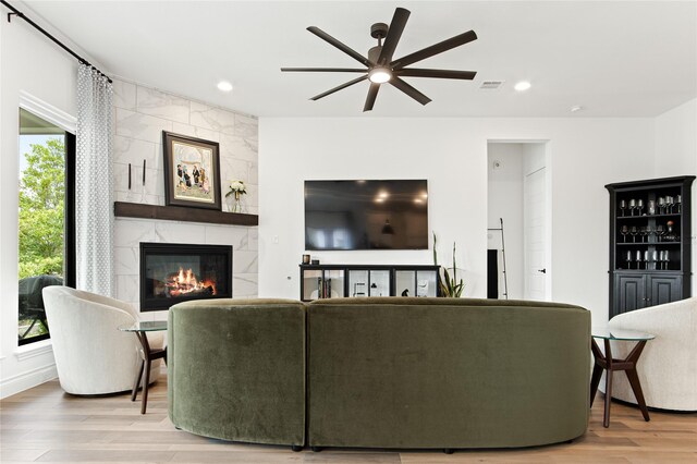 living room featuring a tile fireplace, ceiling fan, and light hardwood / wood-style floors