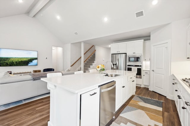 kitchen featuring sink, appliances with stainless steel finishes, an island with sink, beam ceiling, and white cabinets