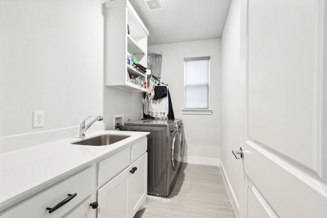 laundry area featuring cabinets, washing machine and clothes dryer, sink, and light tile patterned floors