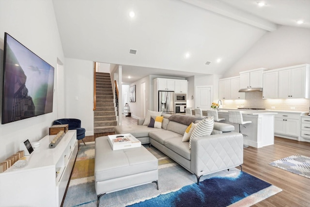 living room featuring high vaulted ceiling, beam ceiling, and light hardwood / wood-style flooring