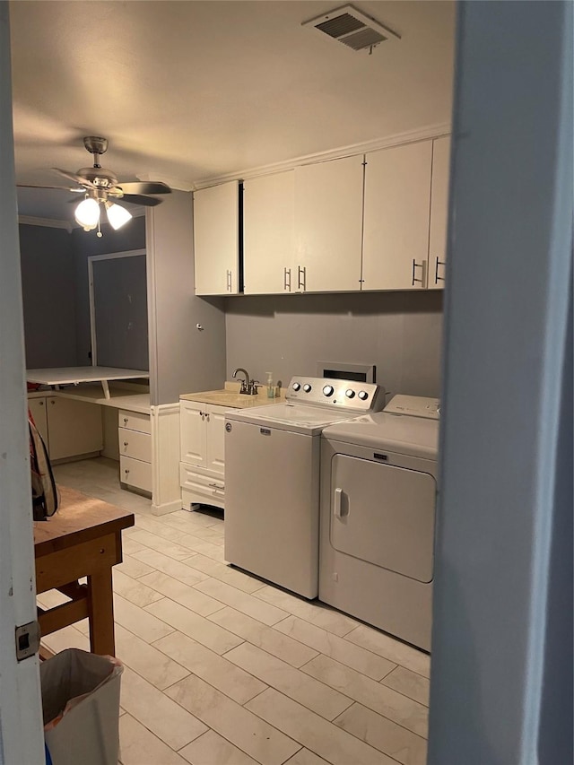 clothes washing area featuring sink, crown molding, cabinets, ceiling fan, and washing machine and dryer