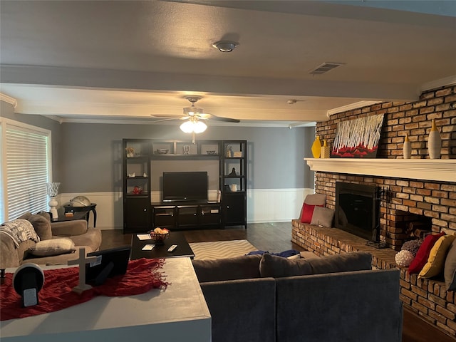 living room featuring beam ceiling, a brick fireplace, ceiling fan, and dark wood-type flooring