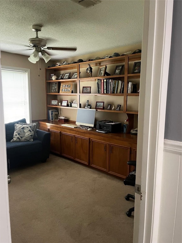 carpeted office featuring a textured ceiling and ceiling fan