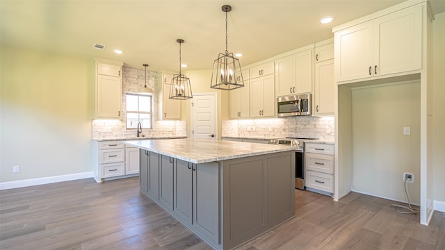 kitchen featuring light stone counters, white cabinets, appliances with stainless steel finishes, and a kitchen island