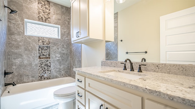 full bathroom featuring tiled shower / bath, vanity, and toilet