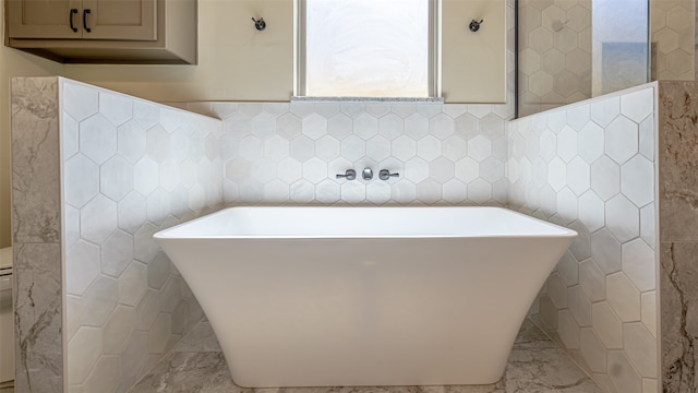 bathroom featuring a washtub and tile walls