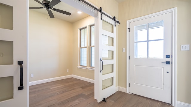 doorway featuring a barn door, hardwood / wood-style flooring, and ceiling fan