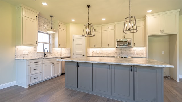 kitchen featuring a kitchen island, dark wood-type flooring, light stone counters, stainless steel appliances, and white cabinets